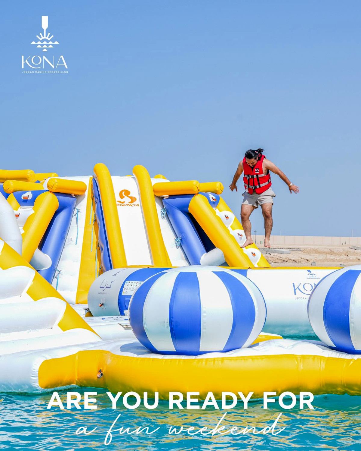 Guest in a life vest bounding across the inflatable water park at Kona Marine Sport Club