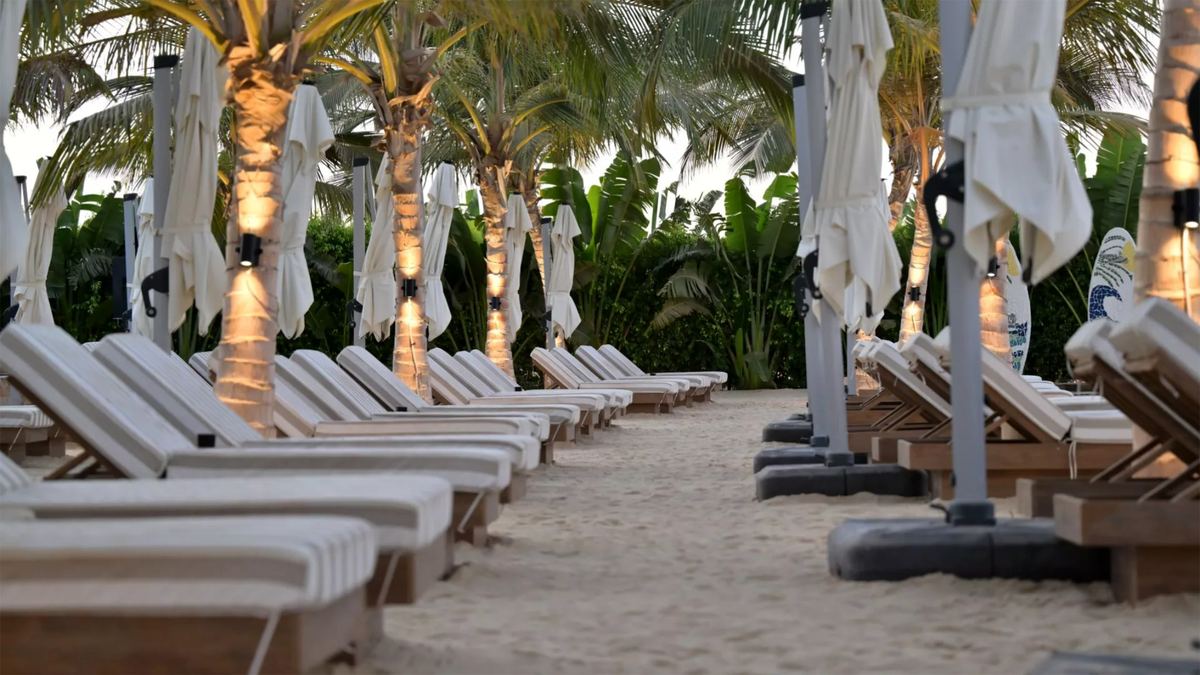 Palm-lined path between cushioned loungers and furled parasols at dusk at Kona Marine Sport Club
