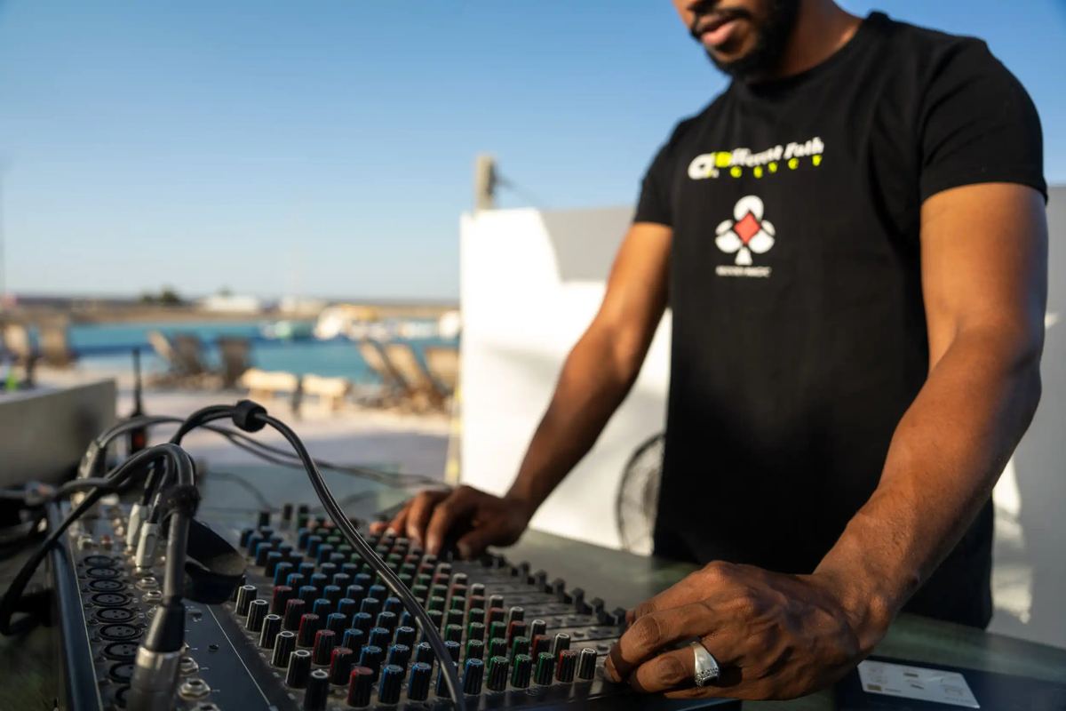 DJ at a mixing desk on the terrace overlooking the lagoon at Kona Marine Sport Club