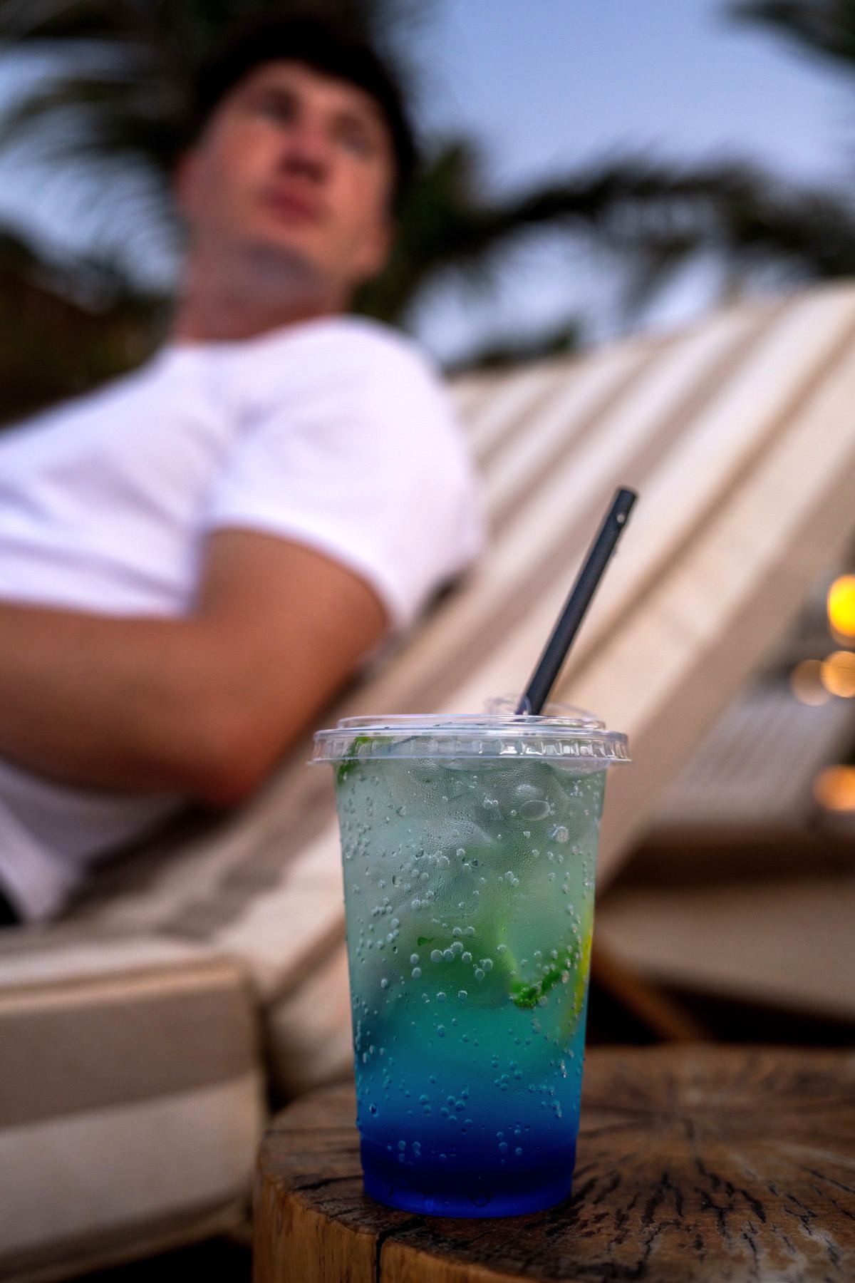 Iced blue mocktail with lime on a wooden side table beside a lounger at Kona Marine Sport Club