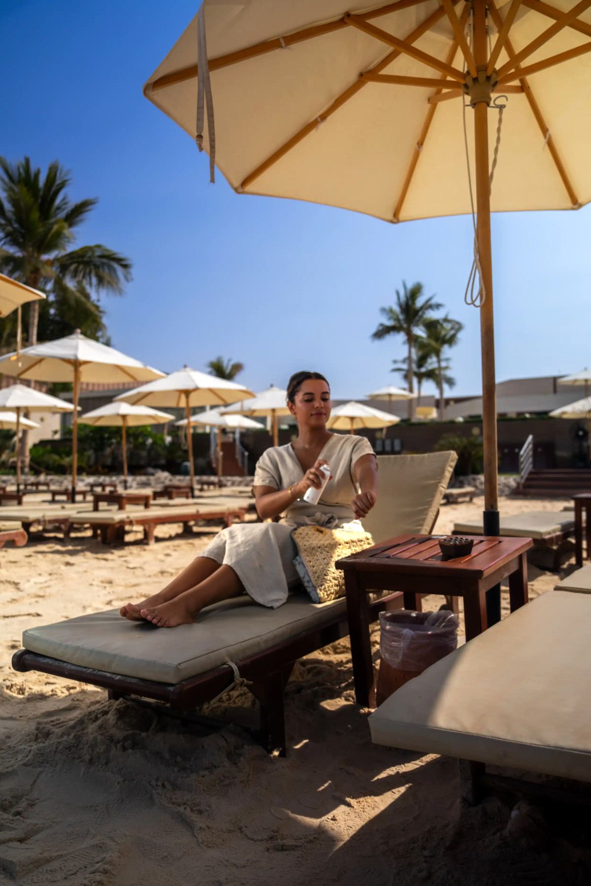 Guest applying sunscreen on a shaded sun lounger at La Maison D’Obhur