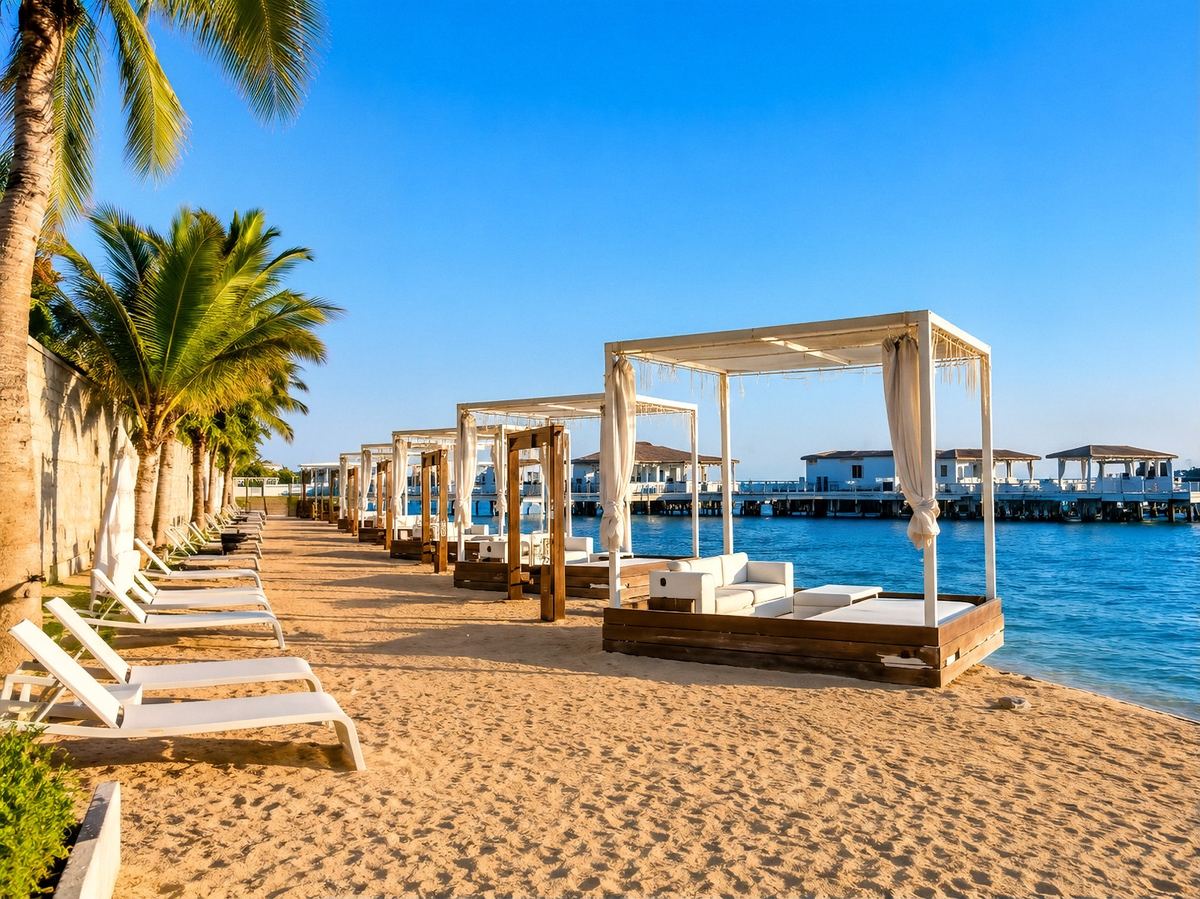 Curtained beach cabanas and white sunbeds along the sandy shore at Mangrove Beach Resort