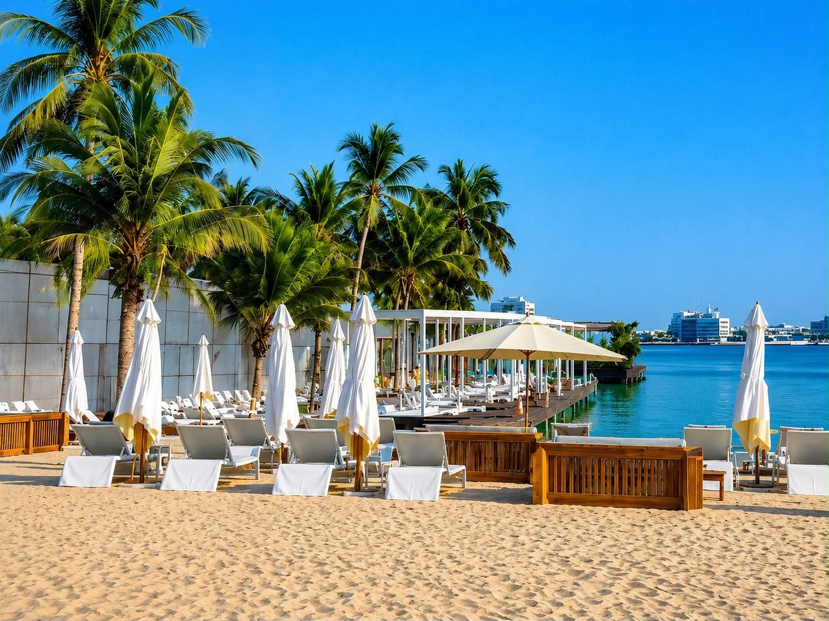 Sunbeds and parasols on the sand beside a waterfront deck at Mangrove Beach Resort