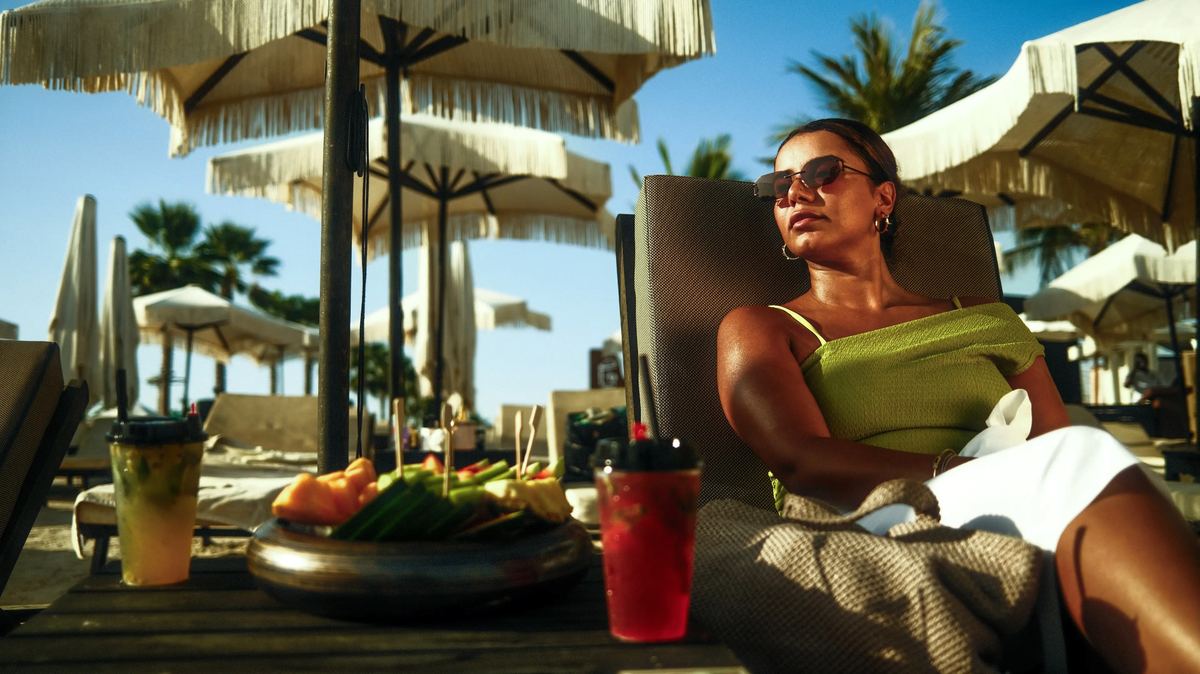 Guest relaxing on a lounger with fresh fruit and mocktails under fringed parasols at Shades Beach Club