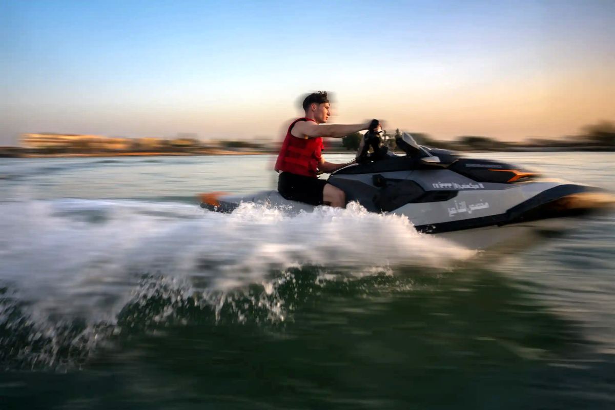 Guest speeding across the water on a jet ski at sunset at Shades Beach Club